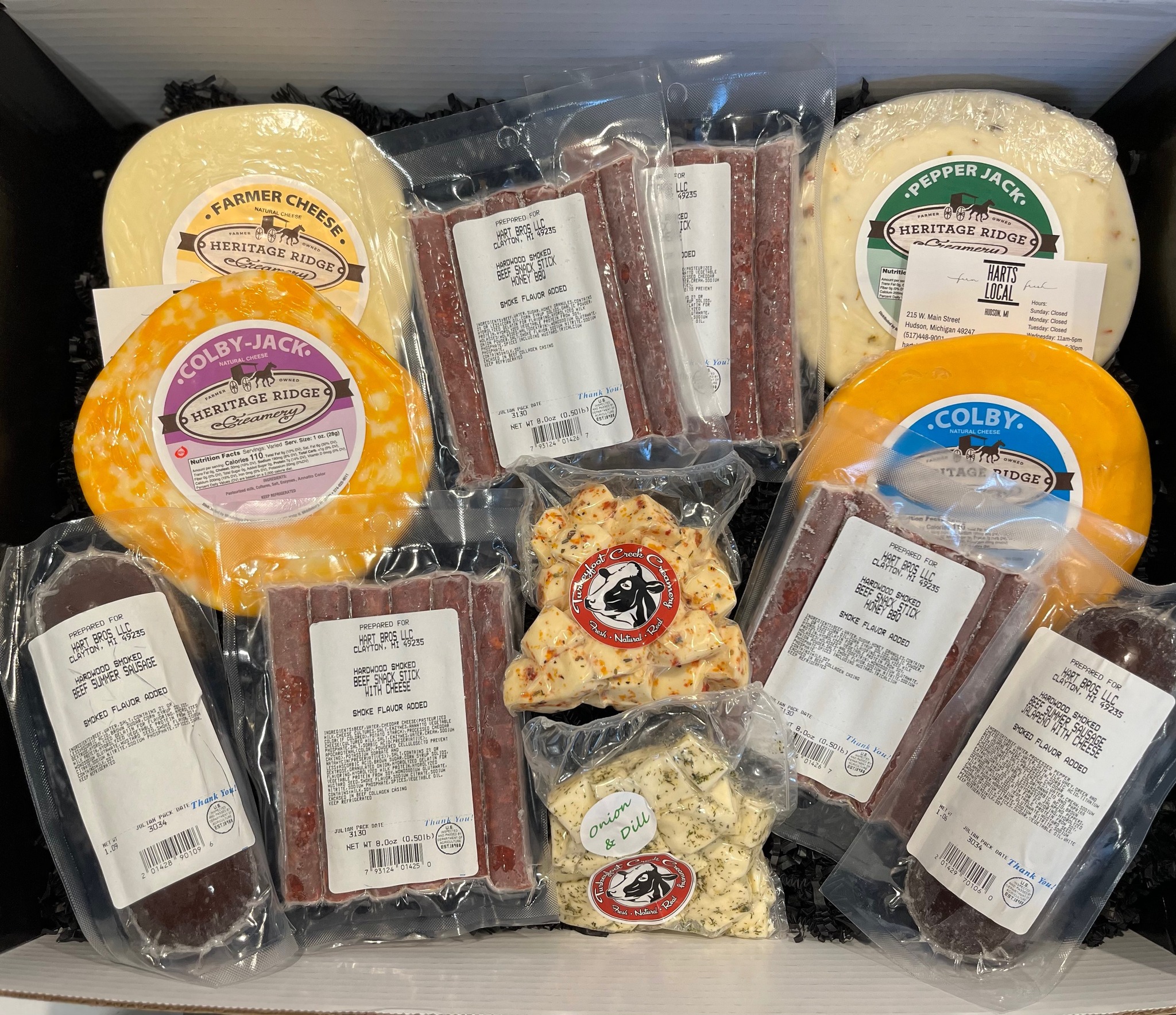 Variety of Heritage Ridge cheese products including Farmer Cheese, Colby-Jack, Pepper Jack, and Colby, alongside assorted beef sticks. The assortment is presented in a box, showcasing a selection perfect for cheese lovers and charcuterie enthusiasts.